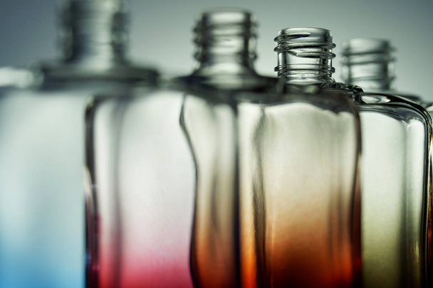 Läpinäkyvät värilliset pullot hajuvettä tai juomia varten kaltevuudella
  - Valokuva, kuva