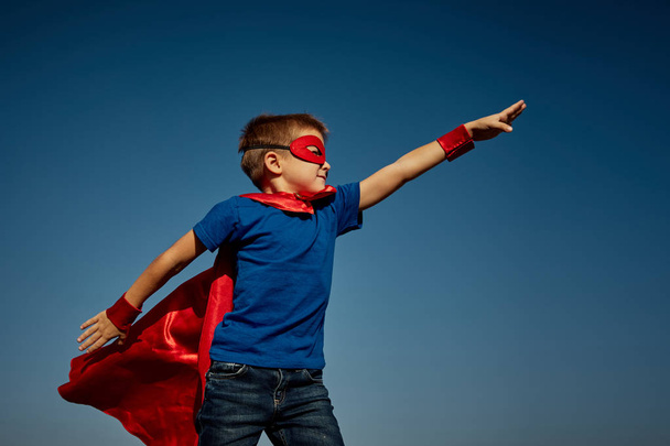 Super hero child (boy) against blue sky - Фото, изображение