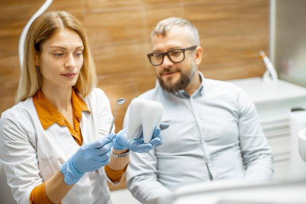 Стоматолог и пациент во время консультации в стоматологическом кабинете
 - Фото, изображение