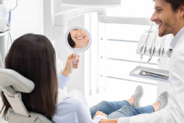 Δυσάρεστη πελάτισσα της οδοντιατρικής κλινικής χαμογελώντας στον καθρέφτη - Φωτογραφία, εικόνα