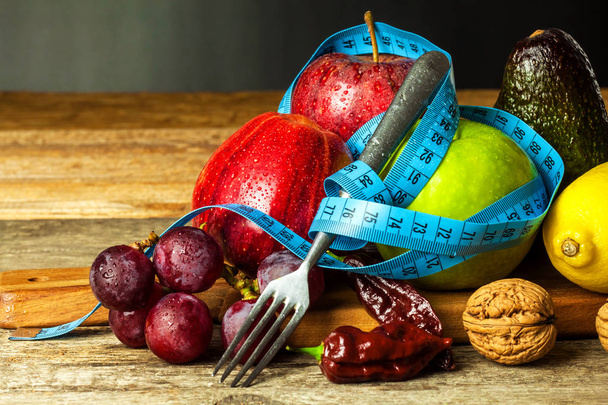 Concept diet.  Healthy food. Fruits on a wooden board wrapped with measuring tape on a wooden table. Weigh loss concept. - Foto, Imagen