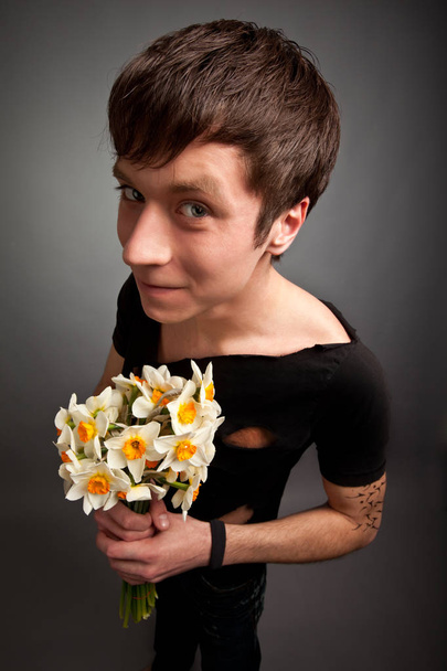 Young man in modern black clothing holding bouquet of narcissus - Fotoğraf, Görsel