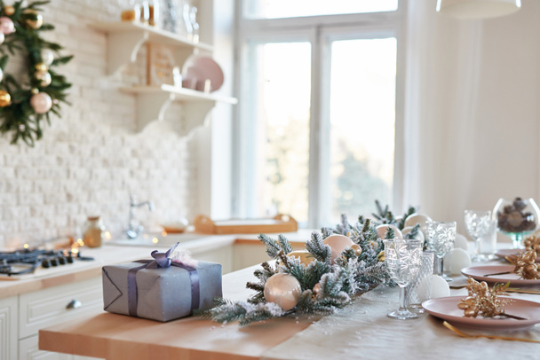 Κουζίνα εσωτερικού φωτισμού με χριστουγεννιάτικη διακόσμηση και δέντρο. Λευκή κουζίνα σε κλασικό στυλ. Χριστούγεννα στην κουζίνα. Φωτεινή κουζίνα σε λευκές αποχρώσεις με Χριστούγεννα. Ρύθμιση Χριστουγεννιάτικου τραπεζιού. - Φωτογραφία, εικόνα