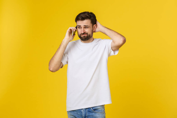Portret van een serieuze man aan de telefoon geïsoleerd op een gele achtergrond. Kijkend naar camera - Foto, afbeelding
