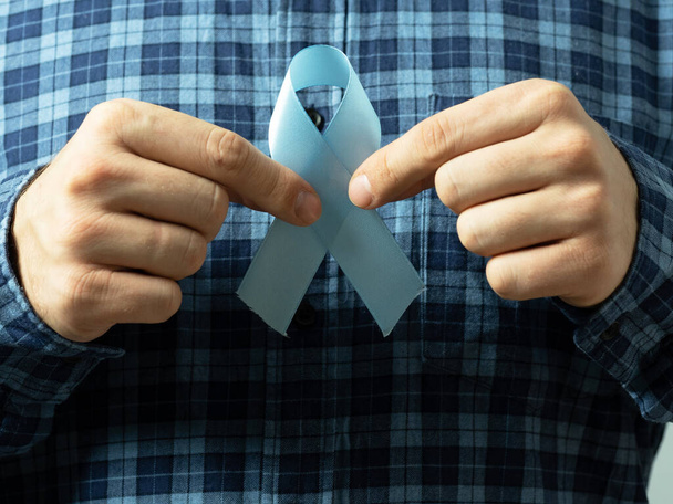 Mężczyzna w koszuli w kratę trzyma dwie ręce niebieską wstążką symbol świadomości raka gruczołu krokowego. Koncepcja medycyny i opieki zdrowotnej dla mężczyzn - Zdjęcie, obraz