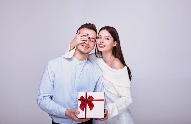 Beautiful couple in love give gifts while closing their eyes on a background. - Foto, Imagem