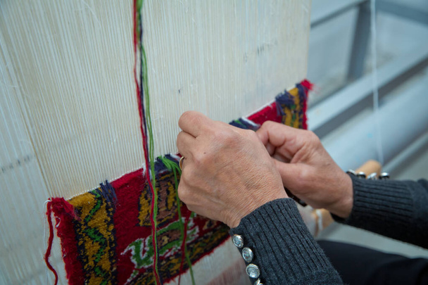 tkaní a výroba ručně vyráběných koberců detailní záběr. ženské ruce spřádají koberec. Ženské ruce tkající koberec . - Fotografie, Obrázek