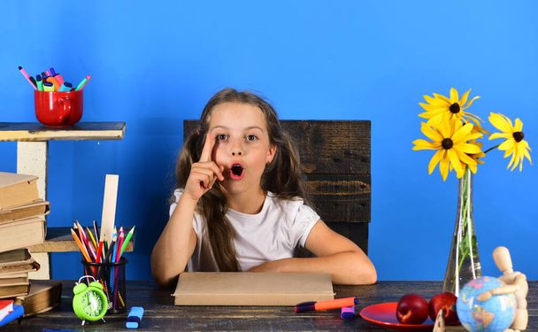 Girl sits at desk with school supplies - Foto, Imagen
