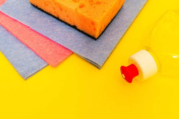 Détergent liquide avec tampon et serviettes différentes couleurs pour le nettoyage sur fond jaune
 - Photo, image