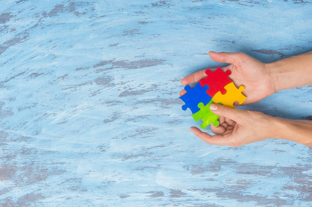 руки, играющие в головоломку символ осведомленности общественности о расстройствах аутизма
. - Фото, изображение
