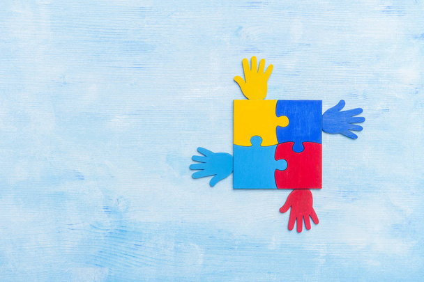 Kolorowe puzzle kawałek i ręce na niebieskim tle. Koncepcja Światowego Dnia Świadomości Autyzmu - Zdjęcie, obraz