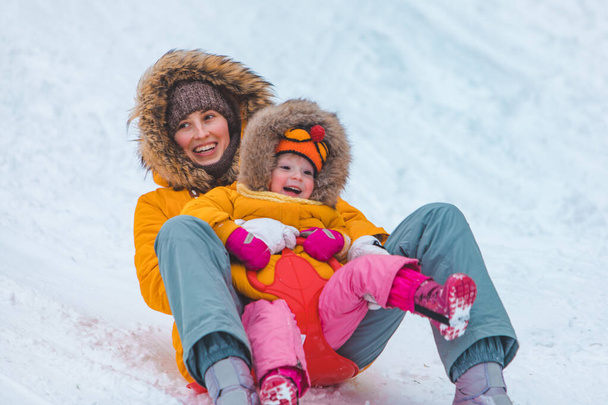 madre con hija deslizándose de la colina de invierno
 - Foto, imagen