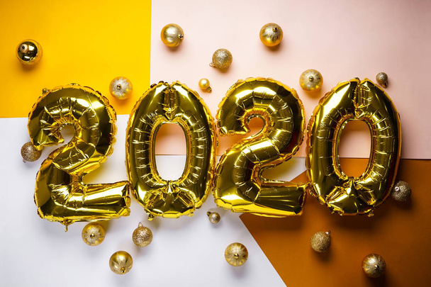 Celebrating the New Year 2020, golden foil balloons 2020 on colorful backgrounds, with golden toys. Foil balls. - 写真・画像