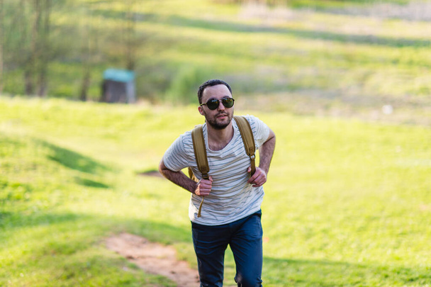 Piesze wycieczki mężczyzna portret z plecaka spacery w przyrodzie. Kaukaski mężczyzna uśmiechający się zadowolony z lasu w tle podczas Letnich podróży - Zdjęcie, obraz