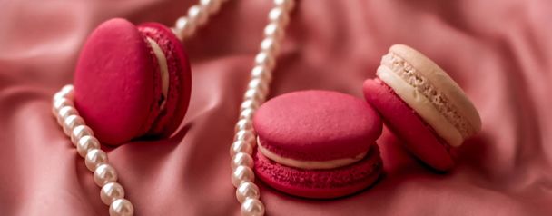 Sweet macaroons and pearls jewellery on silk background, parisia - Foto, Imagen