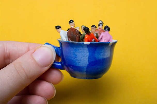 Tasse à main avec des personnages miniatures debout dedans
 - Photo, image