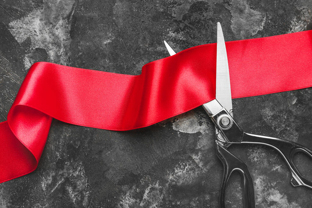 Scissors and red ribbon on grunge background - 写真・画像