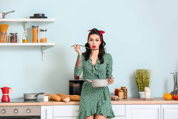 Portrait of beautiful pin-up woman cooking in kitchen - Photo, Image