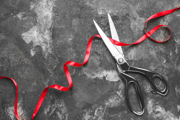 Scissors and red ribbon on grunge background - Photo, Image