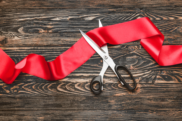 Scissors and red ribbon on wooden background - Valokuva, kuva