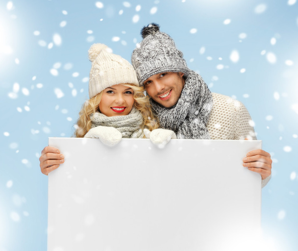 Couple in a winter clothes holding blank board - Φωτογραφία, εικόνα