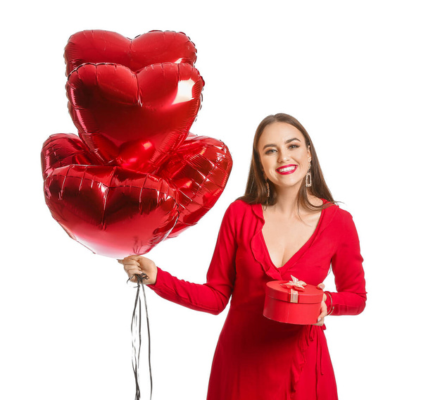 Красива молода жінка з серцеподібними кульками і подарунком на білому тлі. День святого Валентина. - Фото, зображення