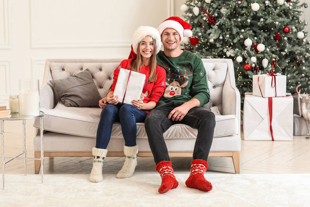 Ευτυχισμένο νεαρό ζευγάρι με Χριστουγεννιάτικο δώρο στο σπίτι - Φωτογραφία, εικόνα