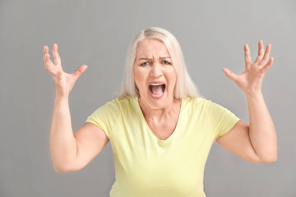 Angry mature woman on grey background - Foto, Imagem