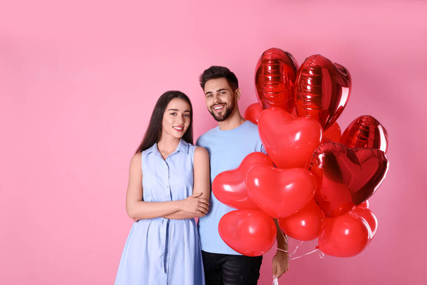Preciosa pareja con globos en forma de corazón sobre fondo rosa. Celebración de San Valentín
 - Foto, Imagen