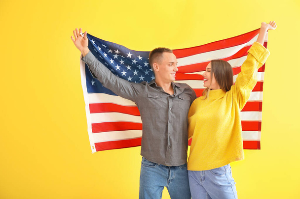 glückliches junges Paar mit US-Nationalflagge auf farbigem Hintergrund - Foto, Bild