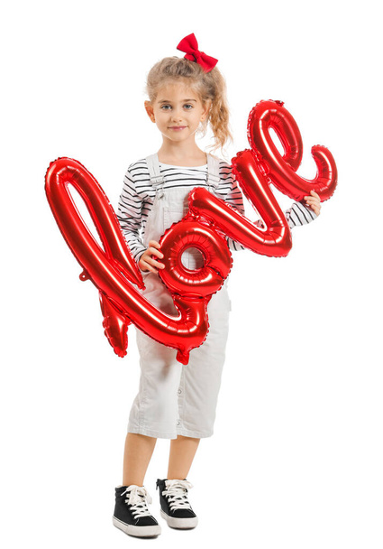 Χαριτωμένο κοριτσάκι με αερόστατο σε σχήμα λέξης Αγάπη σε λευκό φόντο. Γιορτή του Αγίου Βαλεντίνου - Φωτογραφία, εικόνα