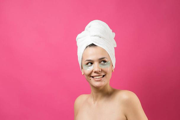 Young beautiful girl in a white towel on his head wears collagen gel patches under her eyes. Mask under eyes treatment face. - Fotoğraf, Görsel