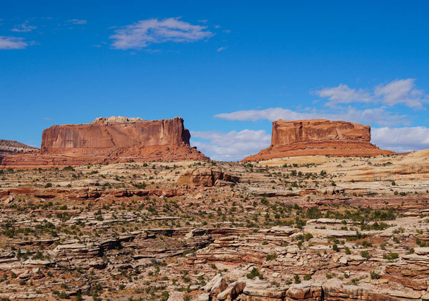 Grandes sentinelas rochosas vermelhas vigiam silenciosamente a estrada para o Parque Nacional de Canyonlands
. - Foto, Imagem