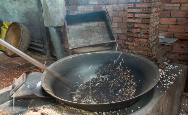 Zčernalá rýžová jádra se začínají objevovat v černé vyhřívané pánvi v Cai - Fotografie, Obrázek