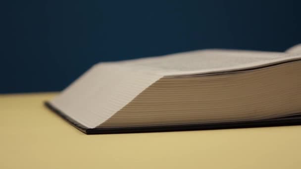 un hombre pasa las páginas de un gran libro negro sobre un fondo azul
 - Metraje, vídeo