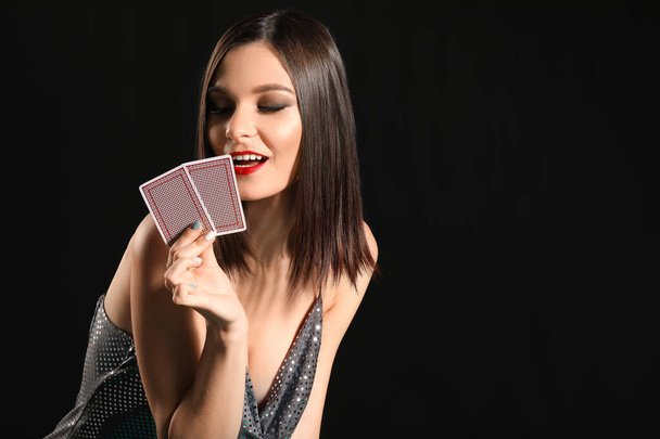 Beautiful young woman with playing cards on dark background - Foto, Imagen