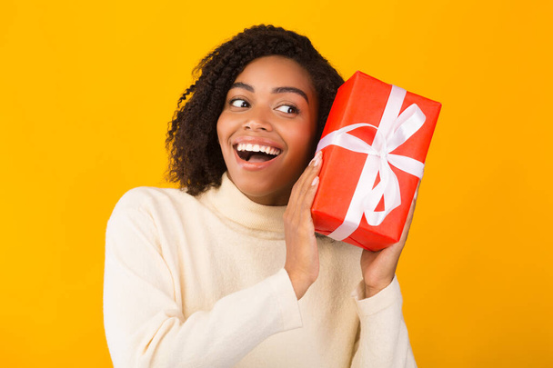 Emocionado chica negra sosteniendo regalo de año nuevo
 - Foto, imagen