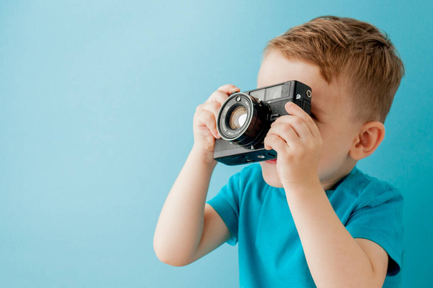Mały chłopiec ze starą kamerą na niebieskim tle - Zdjęcie, obraz
