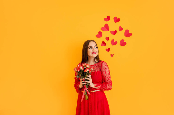 Gyönyörű fiatal nő, virágokkal és piros szívekkel, színes háttérrel. Valentin-napi ünneplés - Fotó, kép