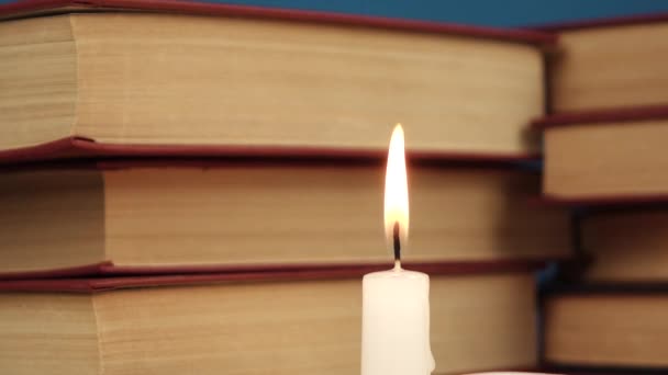 une seule bougie blanche brûle contre un tas de livres
 - Séquence, vidéo