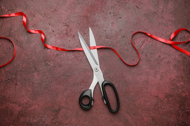 Scissors and red ribbon on color background - Photo, image