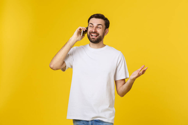 mladý ležérní muž mluví po telefonu izolované na žlutém pozadí - Fotografie, Obrázek