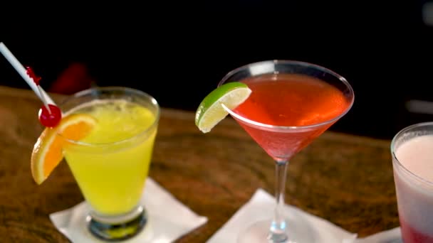 Drie glazen met veelkleurige alcoholische dranken op bar, close-up van cocktails - Video