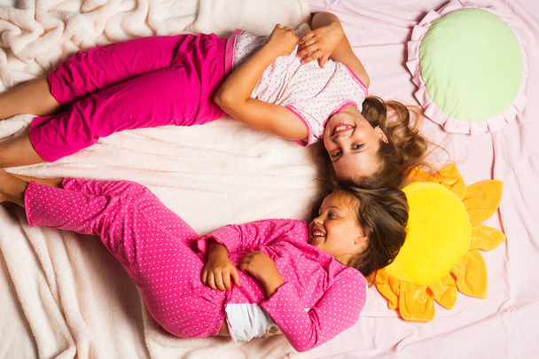 Children with happy faces lie close on pink blanket background. - Foto, Imagem