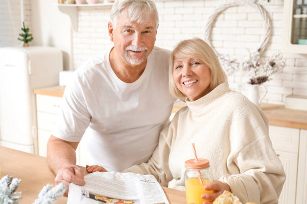 Happy mature couple having breakfast in kitchen - Photo, Image