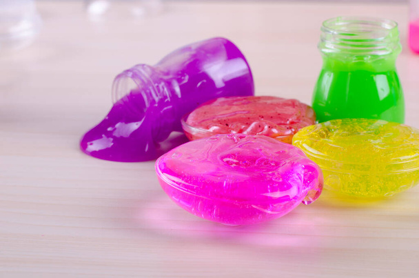 Slimes multicolori lucenti su un tavolo. Giocattolo popolare dei bambini di oggi. Bava in contenitori di plastica
. - Foto, immagini