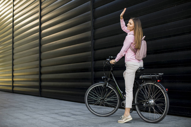 Mujer bastante joven montando una bicicleta eléctrica en el entorno urbano
 - Foto, Imagen