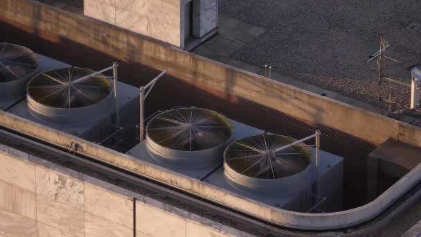 Zamknij widok z powietrza patrząc w dół na dużych wentylatorów klimatyzatorów na dachu, gdy biegają i obracają się w letni dzień na dachu w wieżowcu w centrum Chicago. - Materiał filmowy, wideo