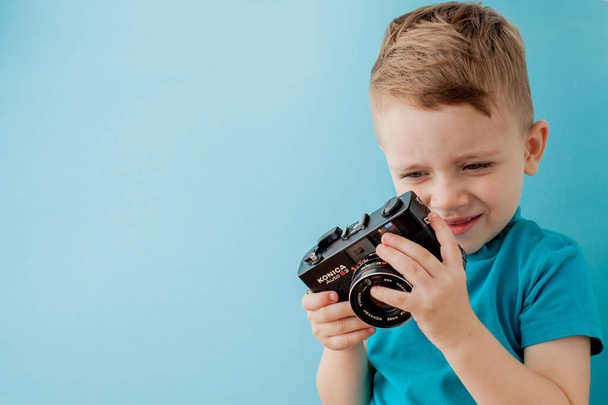 Little boy with an old camera on a blue background - Zdjęcie, obraz