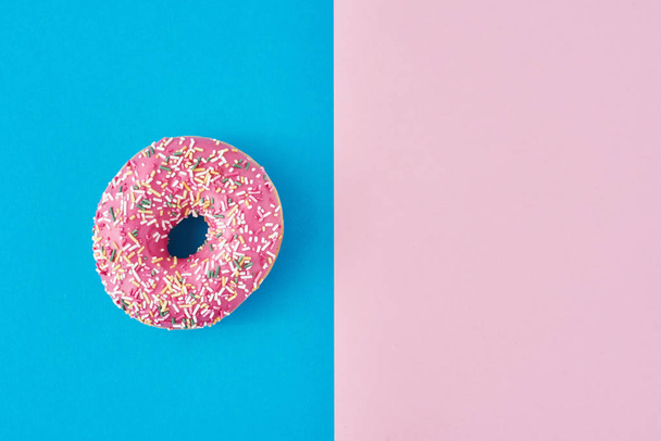 donitsi pastelli vaaleanpunainen ja sininen tausta. Minimalismi luova elintarvikkeiden koostumus. Tasainen lay tyyli
 - Valokuva, kuva